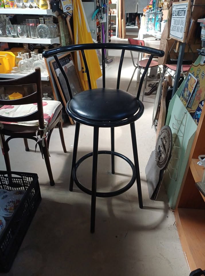 Tabouret de bar pivotant à 360°, en métal noir avec assise rembourrée en similicuir noir.